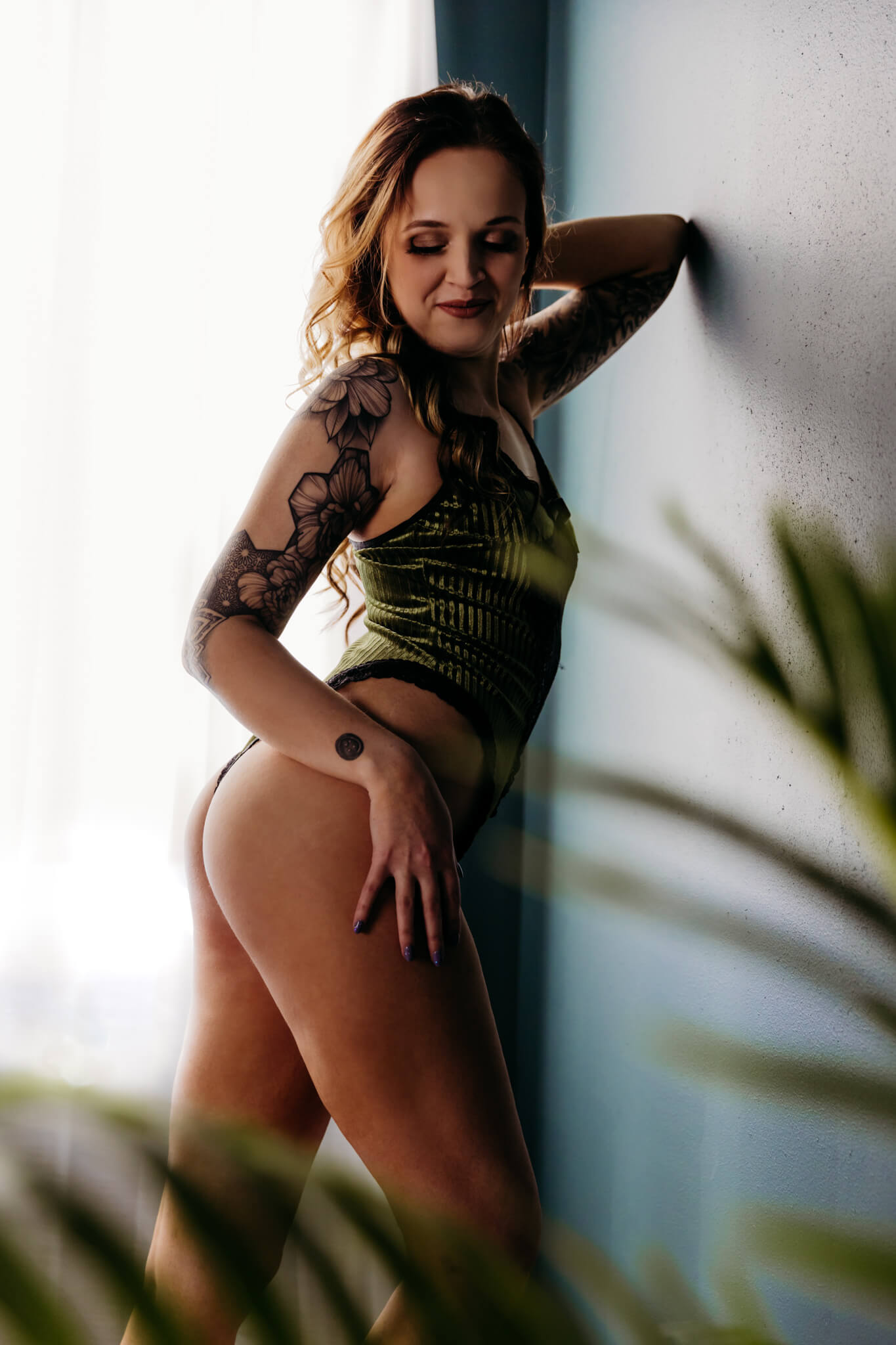 woman in a green outfit leaning against the wall looking back