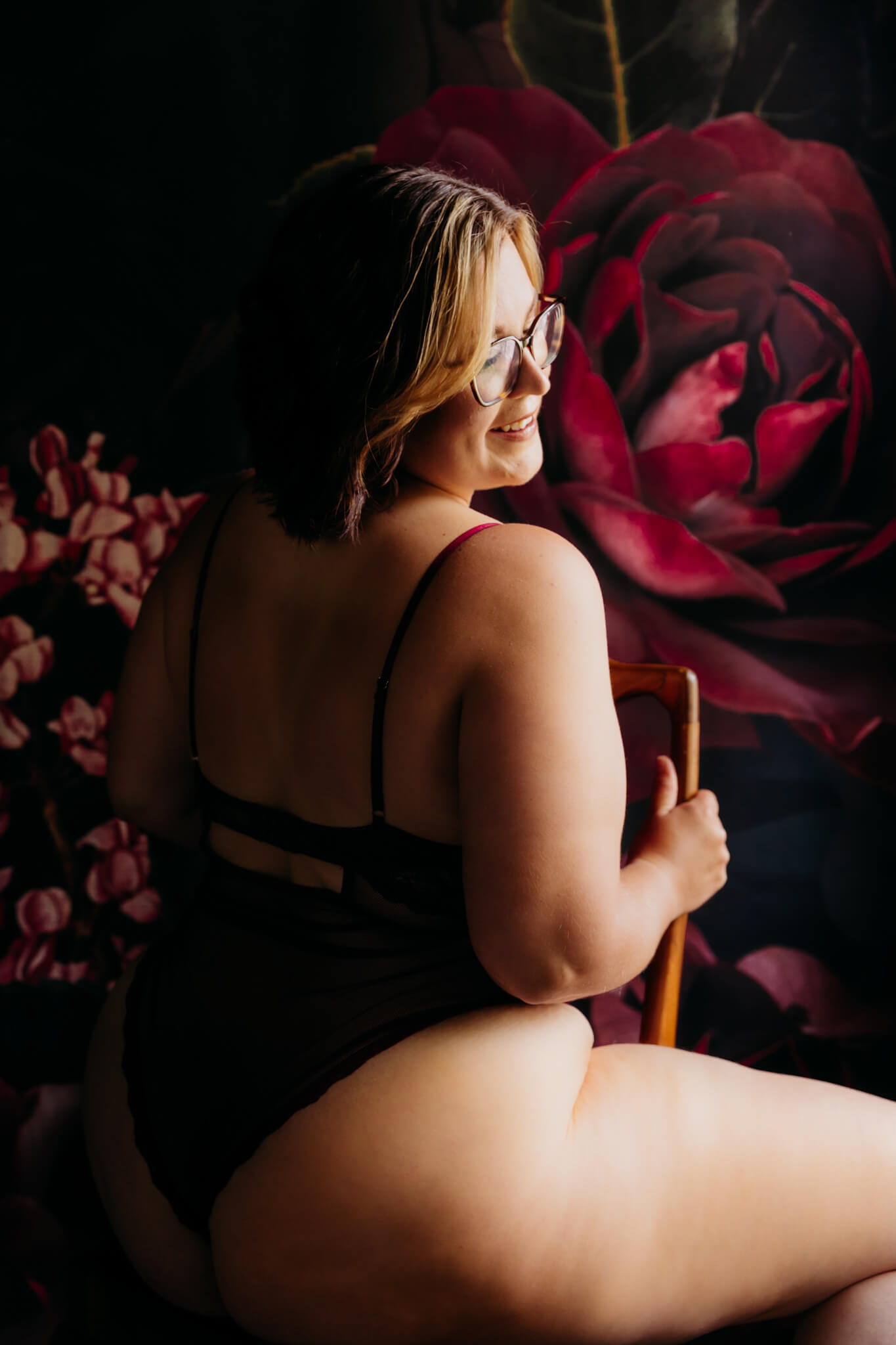 woman in a red outfit sitting on a chair in front of a red rose background