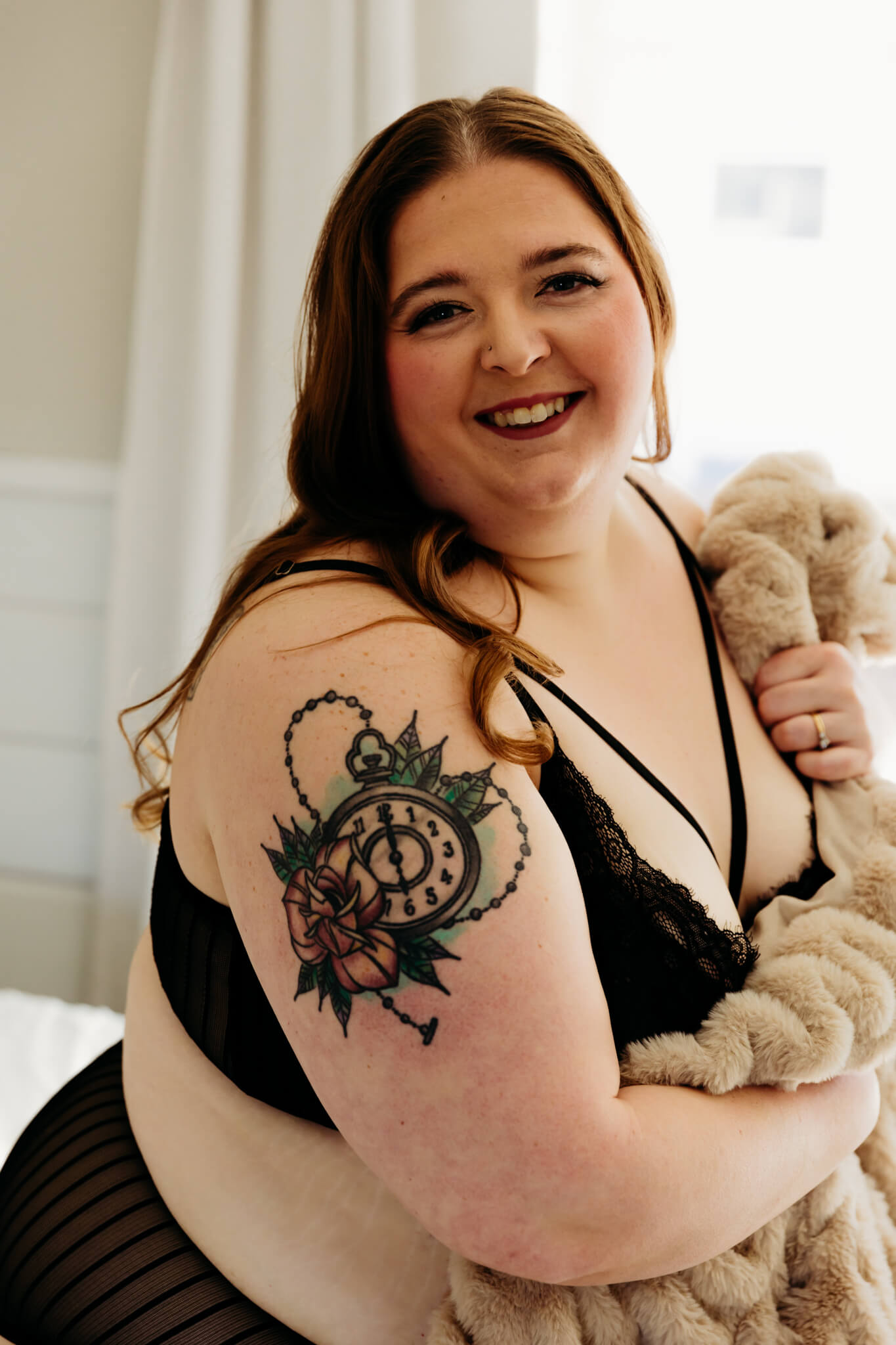 woman in a black two piece outfit holding a blanket and smiling for a blog about nicoles boudoir experience