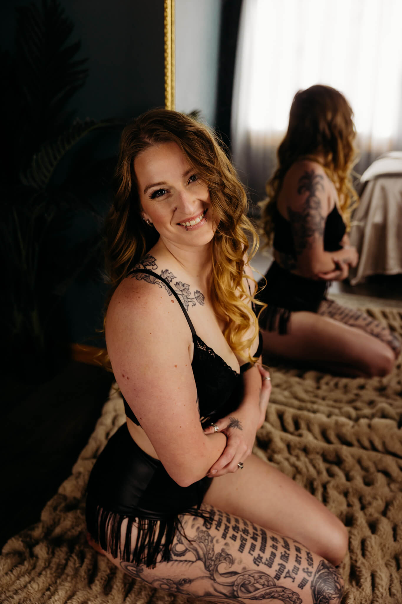 image from Monica's boudoir session where she's giving herself a hug as she sits in front of a mirror