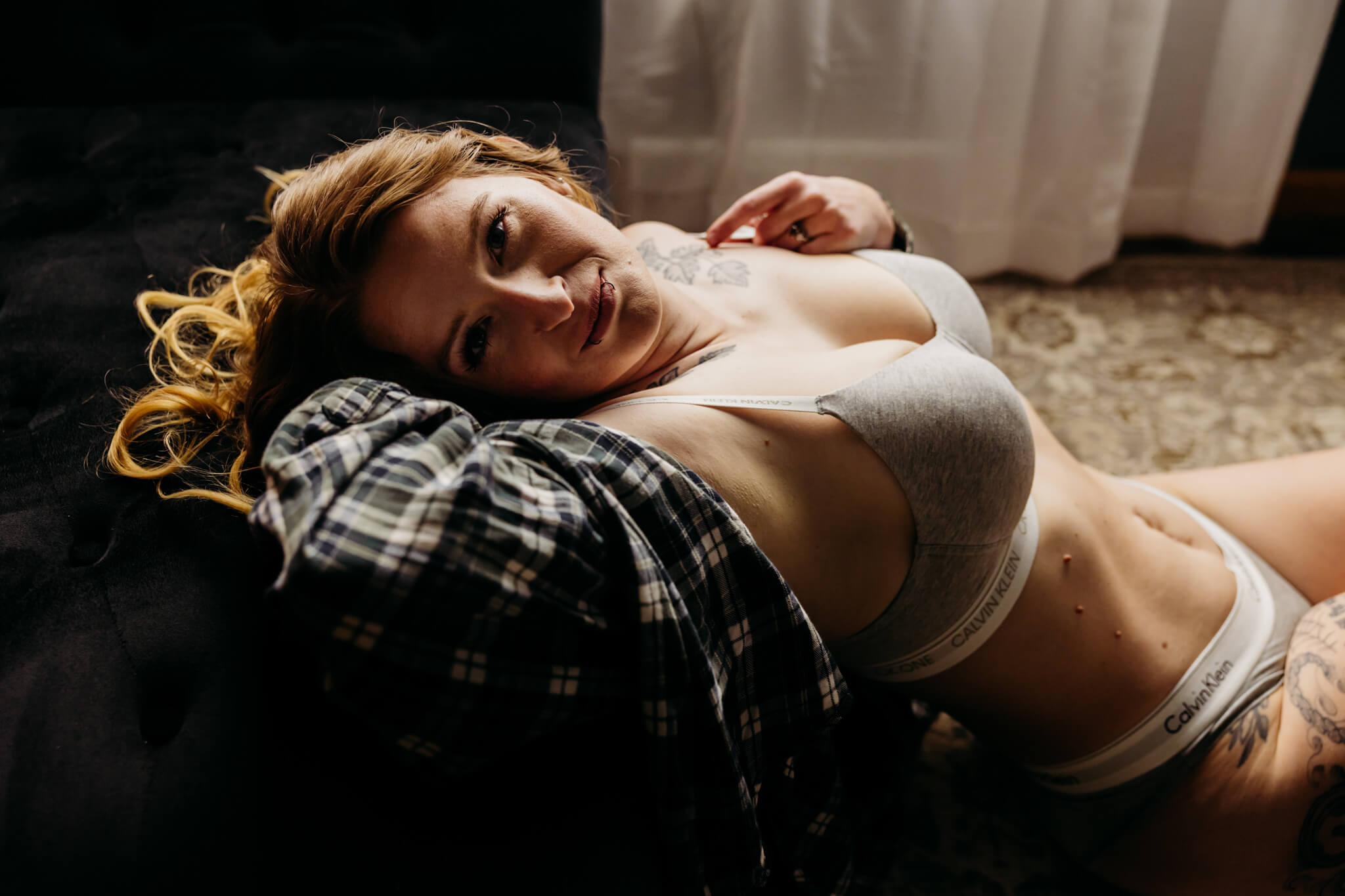 stunning woman laying her head back on a black chaise as she looks over confidently